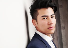 Close-up portrait of a serious Asian man in a formal suit indoors. Modern and professional look.