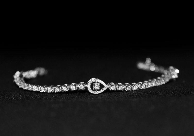Close-up of a luxurious diamond bracelet with a black backdrop, showcasing elegance.