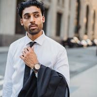 Young businessman in white shirt holding jacket on city street.
